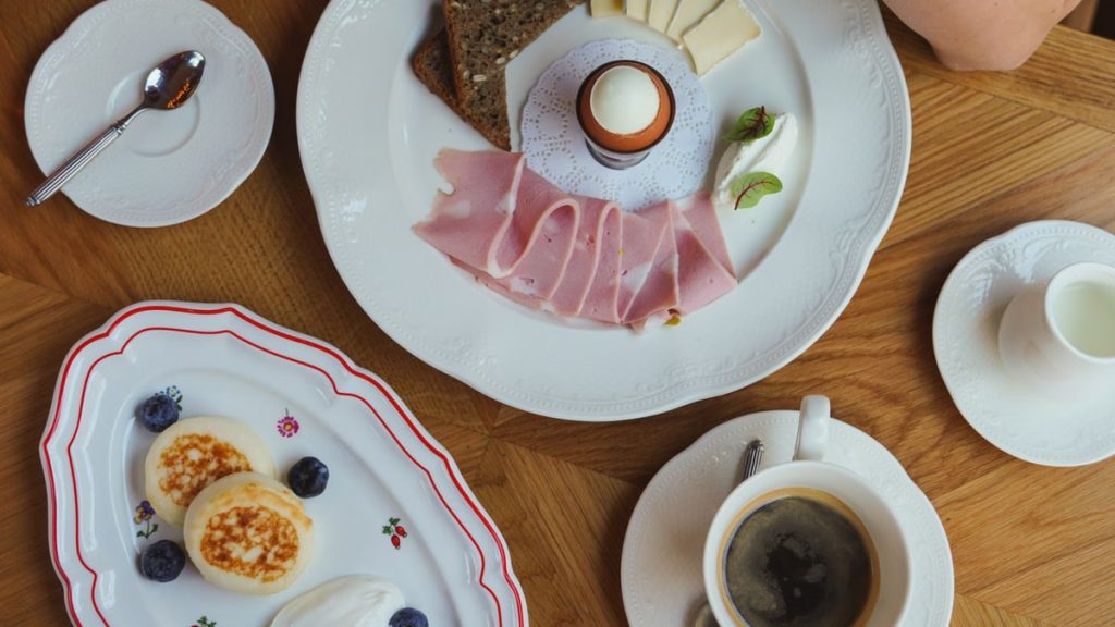 A sophisticated breakfast spread featuring coffee, ham, eggs, and cheese on a wooden table.